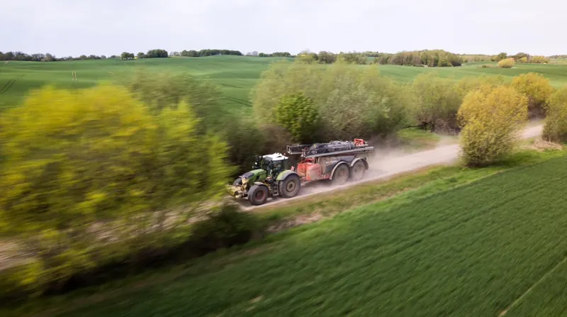 Fendt mit Horsch Feldspritze auf staubigem Feldweg